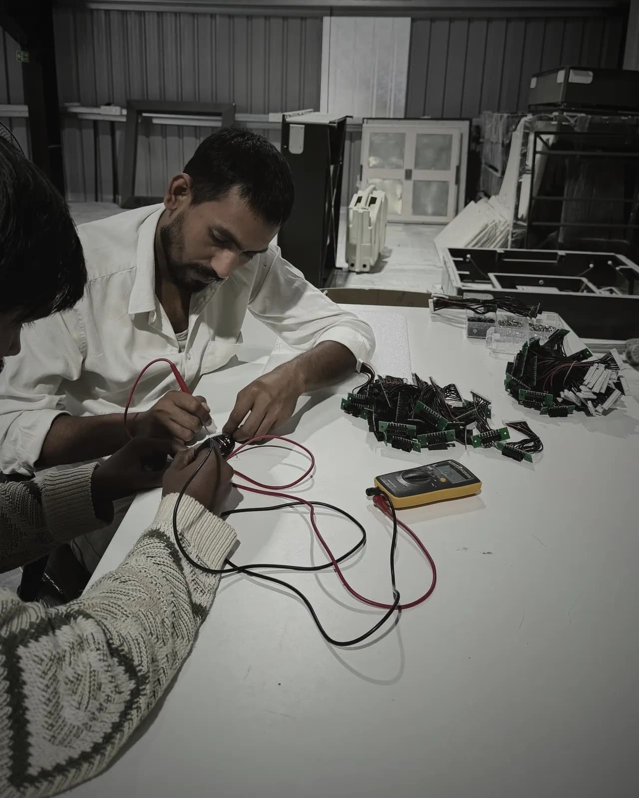 Technicians continuity-testing battery balance-lead harnesses