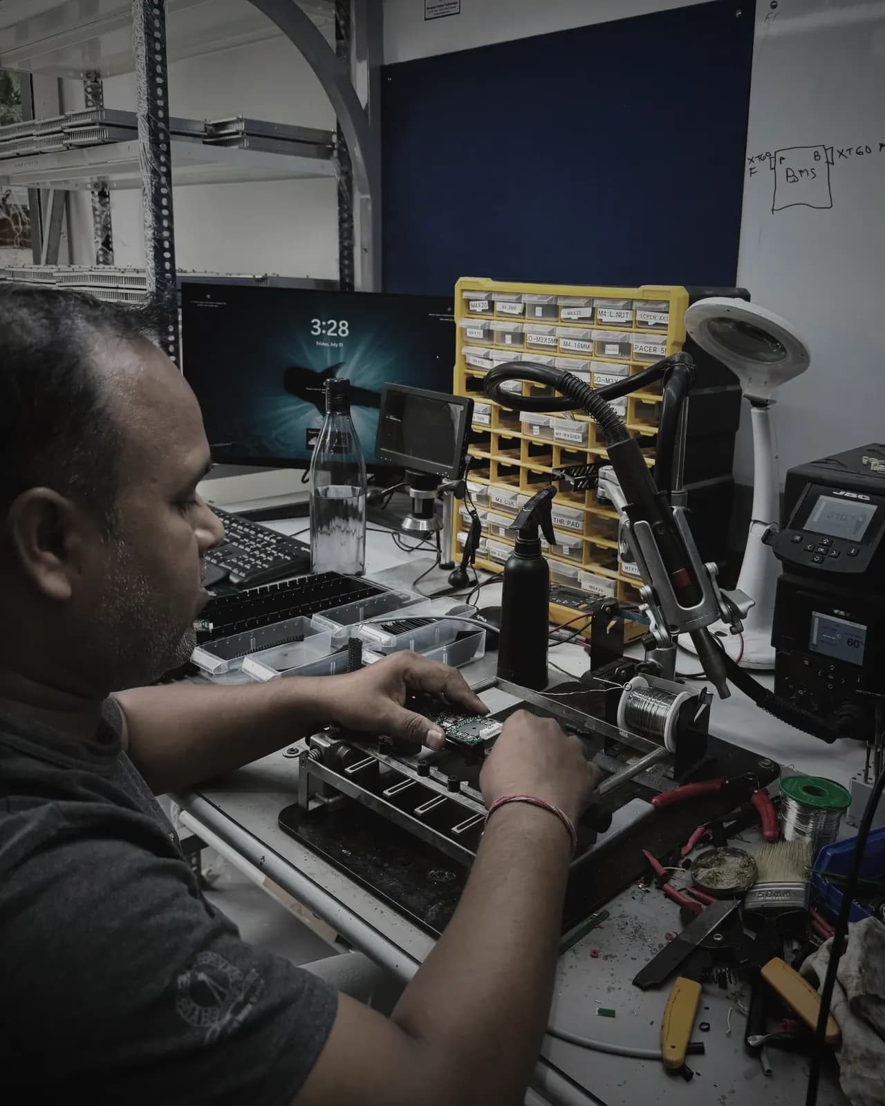 Technician seating a BMS circuit board in a soldering fixture